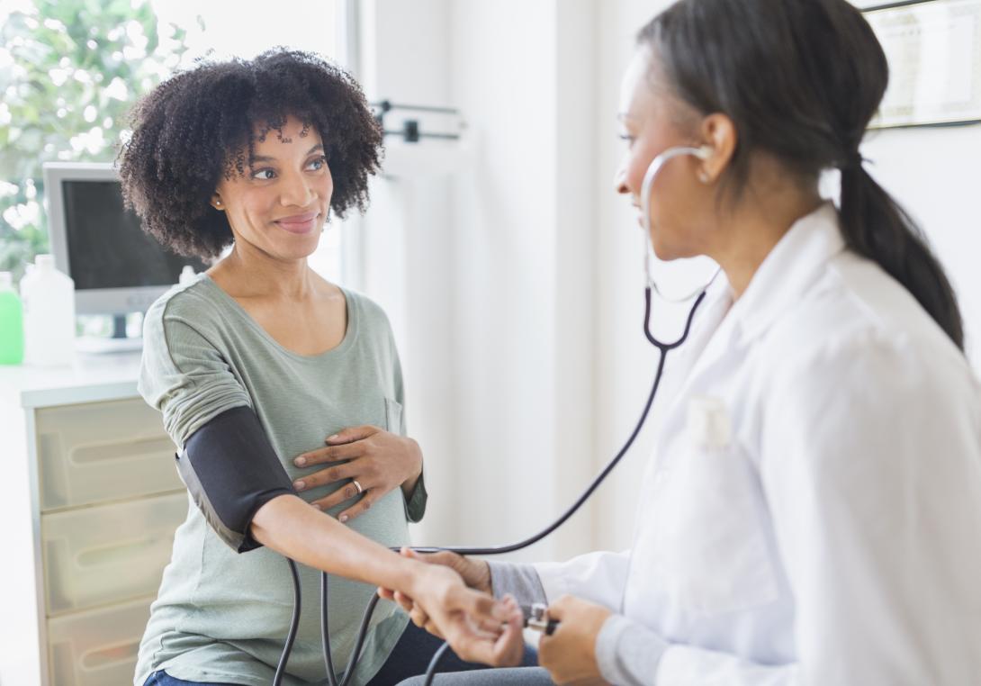 Doctor using a stethoscope listening to pregnant woman's belly